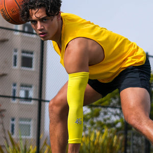 A basketball player dribbling while looking into the camera with a yellow arm sleeve #45 on the wrist.